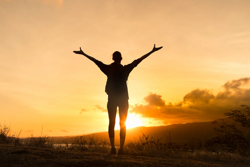 Woman stretching out her arms looking at the sunset